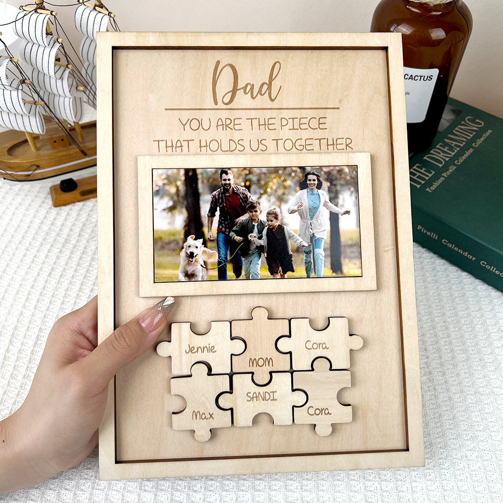 A wooden frame with a family and puzzle engraved with names of each family