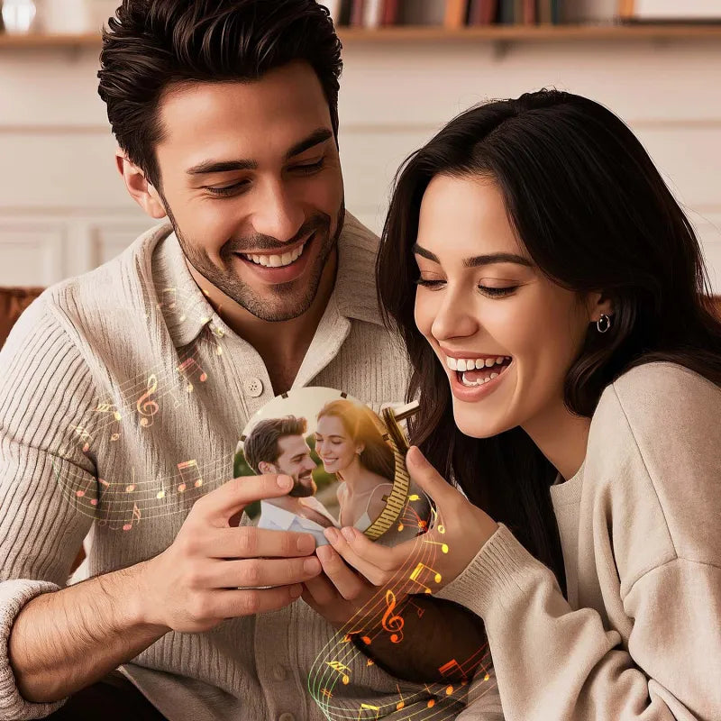 Man and woman holding a photo album with a smiling couple on the cover, sitting together.