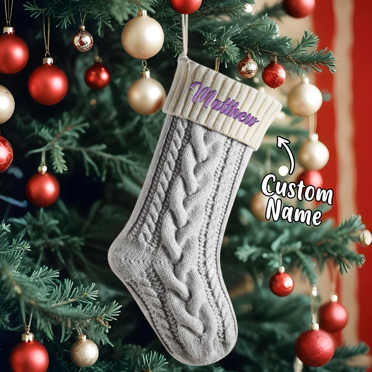 Gray knitted Christmas stocking with 'Matthew' embroidered on it, hanging on a decorated tree.