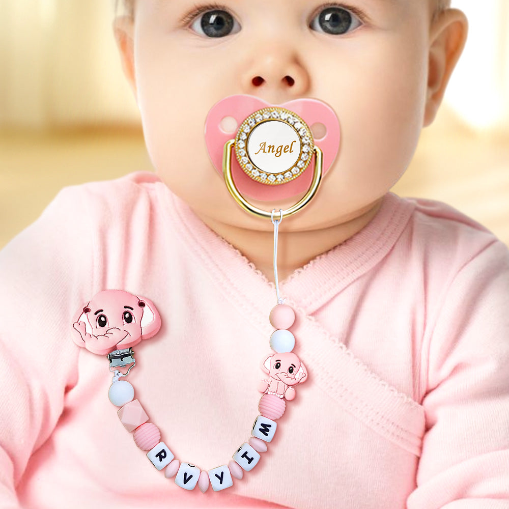 Baby wearing a pink pacifier with decorative chain and 'Angel' charm