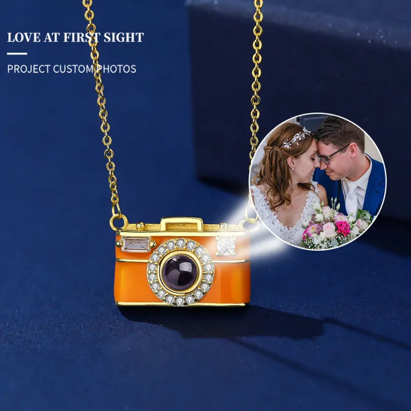 Camera-shaped necklace with a photo inset of a couple on a blue background