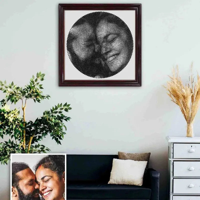 Framed artwork of two faces on a wall above a couch with decorative elements.