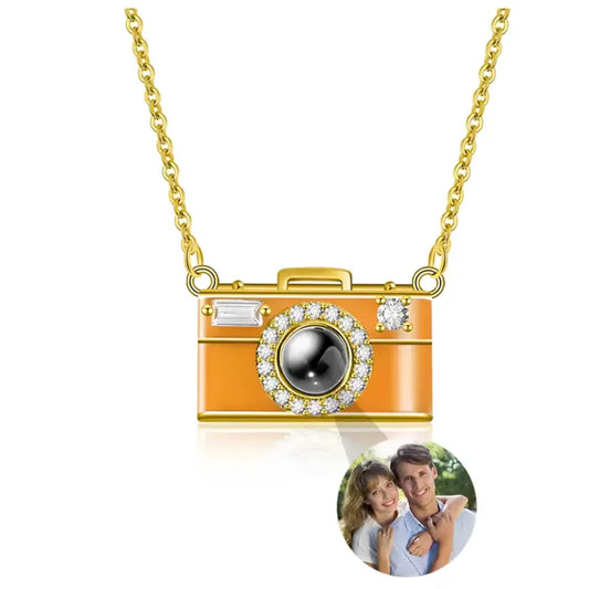 Camera-shaped pendant necklace with gold chain on a white background
