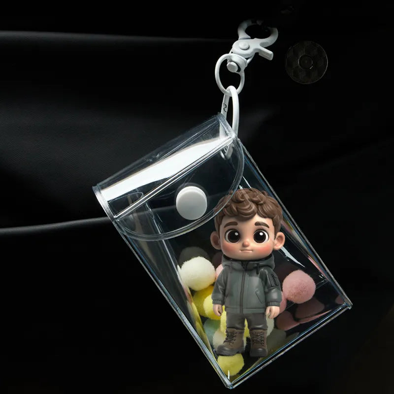 Clear plastic keychain with a small figurine of a boy holding a teddy bear on a dark background