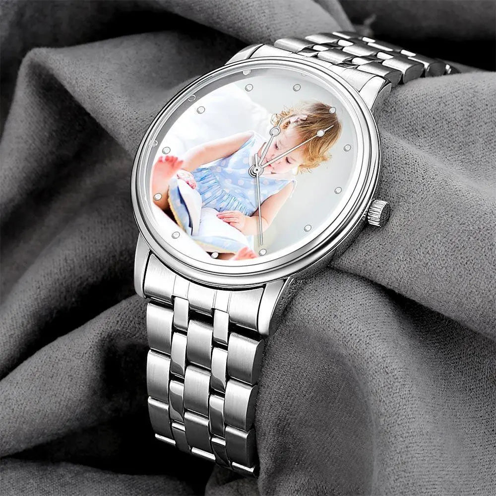 Silver watch with a photo of a child on the dial, displayed on gray fabric.