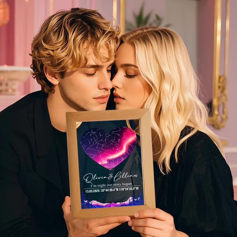 Two people holding a framed heart-shaped astrophotograph with constellation design.