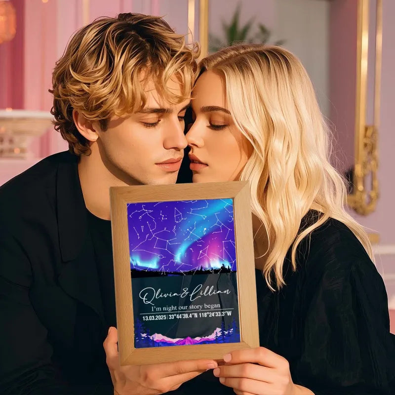 Two people holding a framed artwork with a starry night design and text.