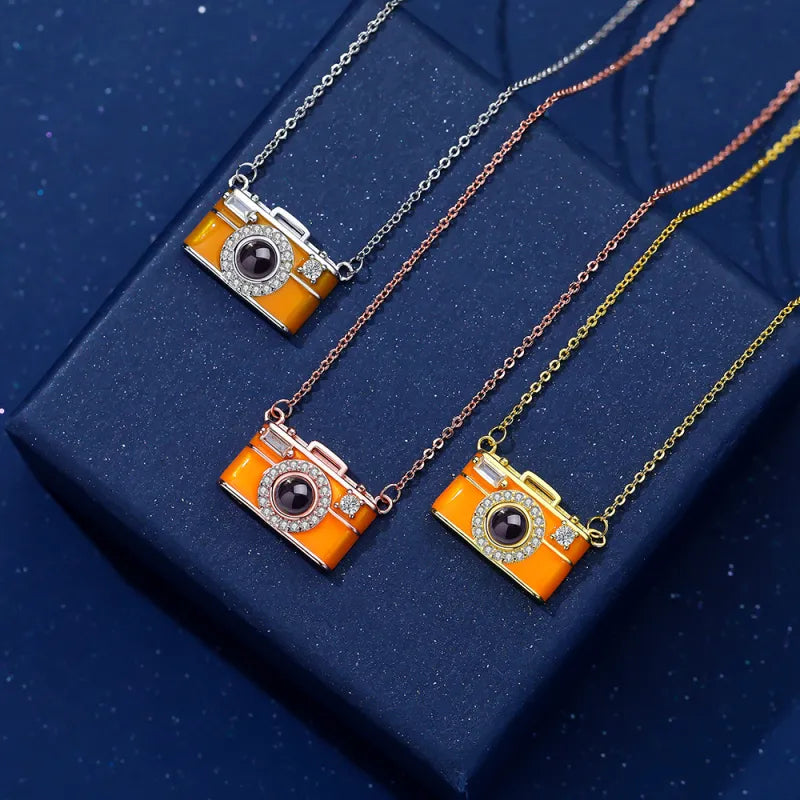Camera-shaped pendants on chains against a blue background