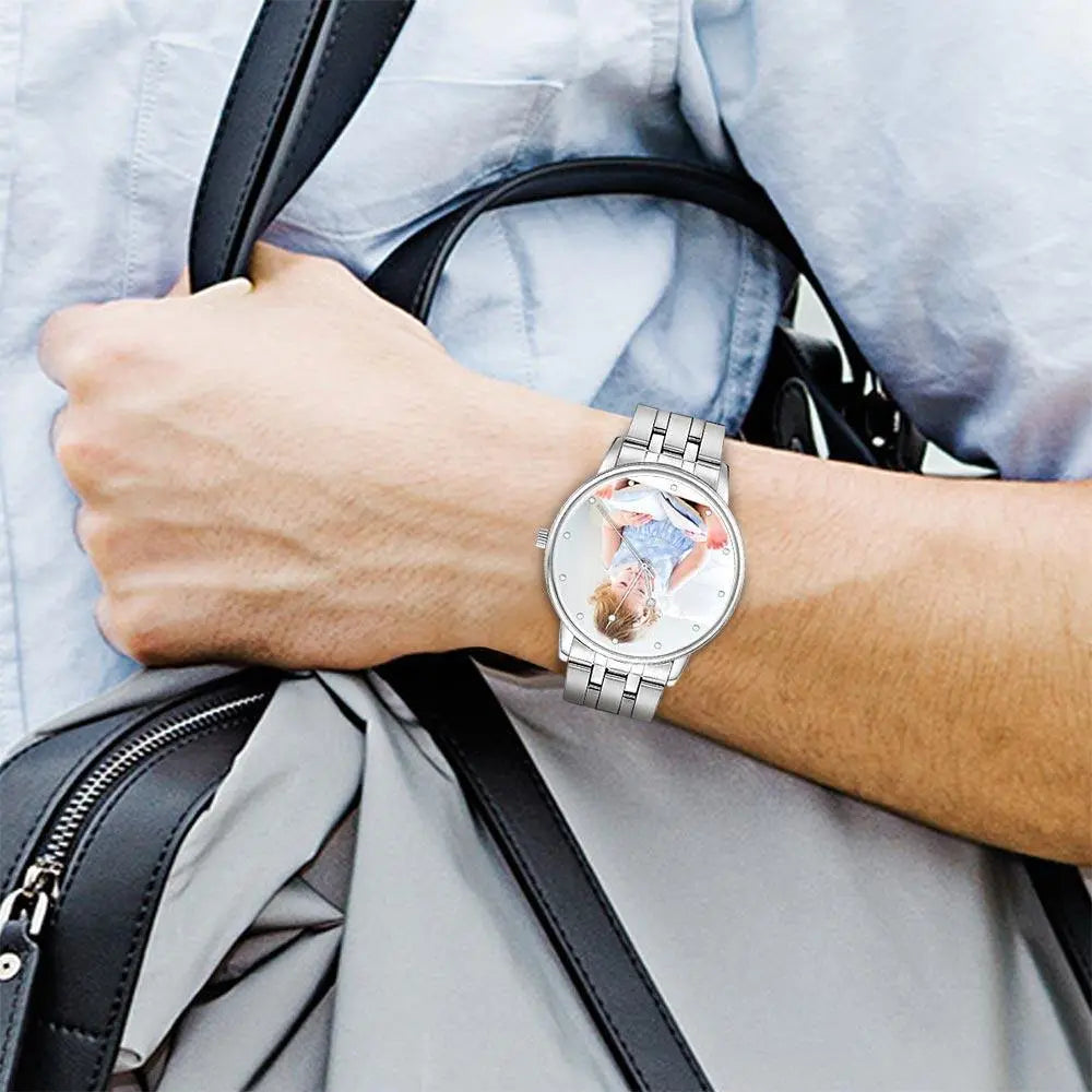 Person wearing a watch with a detailed face, holding a black handbag.