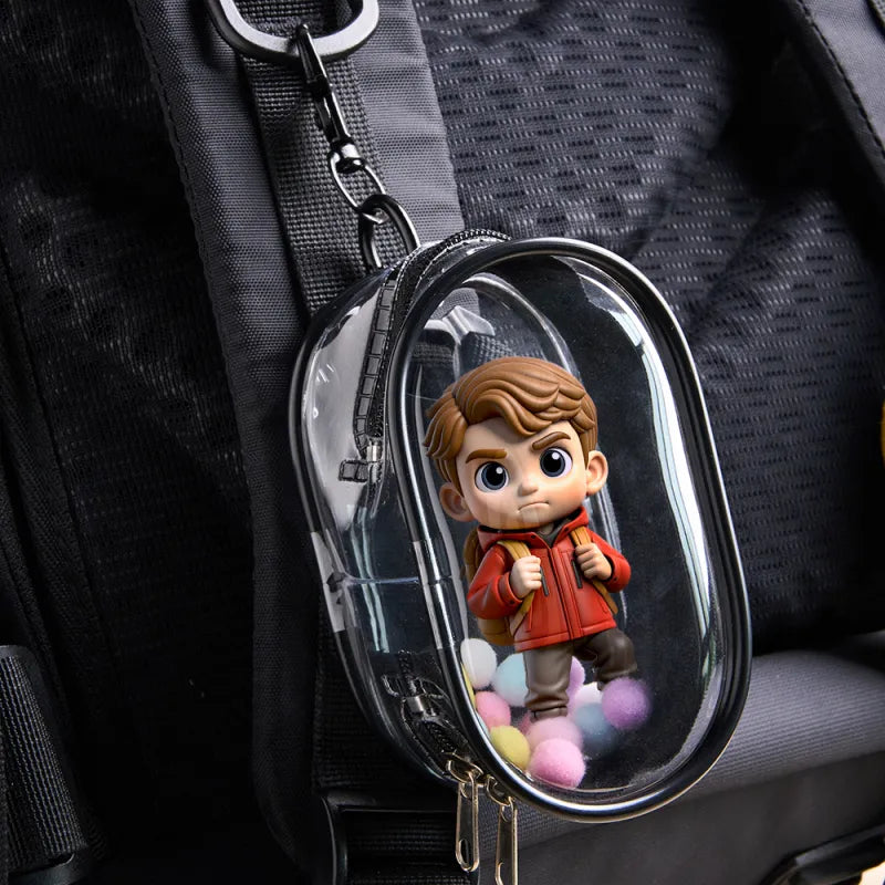 Keychain with a small figurine of a boy in an orange jacket inside a clear dome on a dark background.