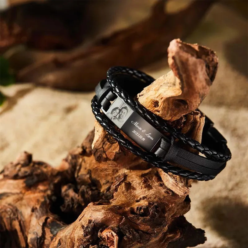 Black braided bracelet with engraved details on a wooden surface