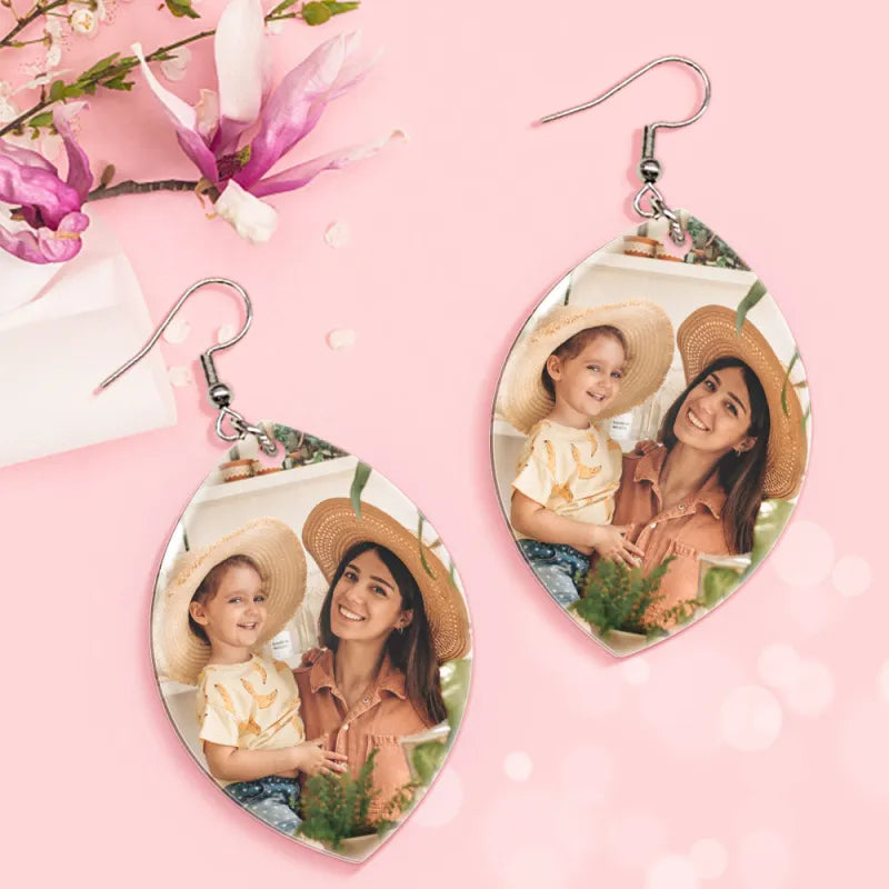 Heart-shaped photo earrings on a pink background with flowers