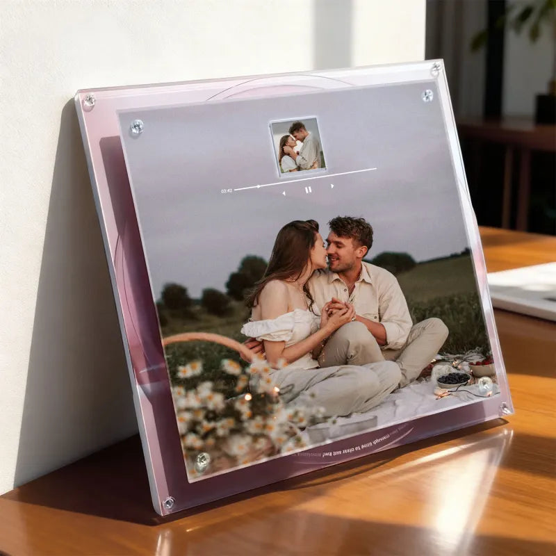 Acrylic photo stand with a couple in a field on a wooden surface