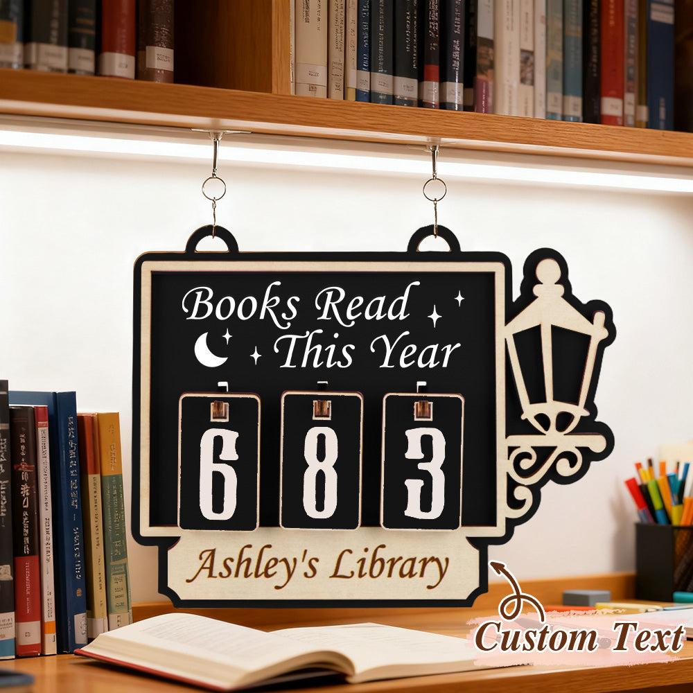 Flip clock-style sign with 'Books Read This Year' and 'Ashley's Library' text, hanging on a bookshelf.