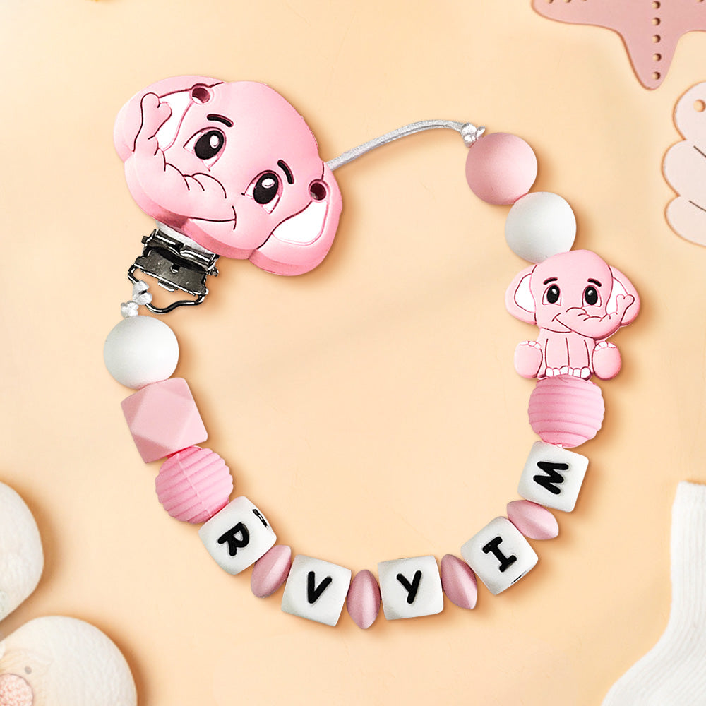 Pink baby teether with cartoon character design on a beige background