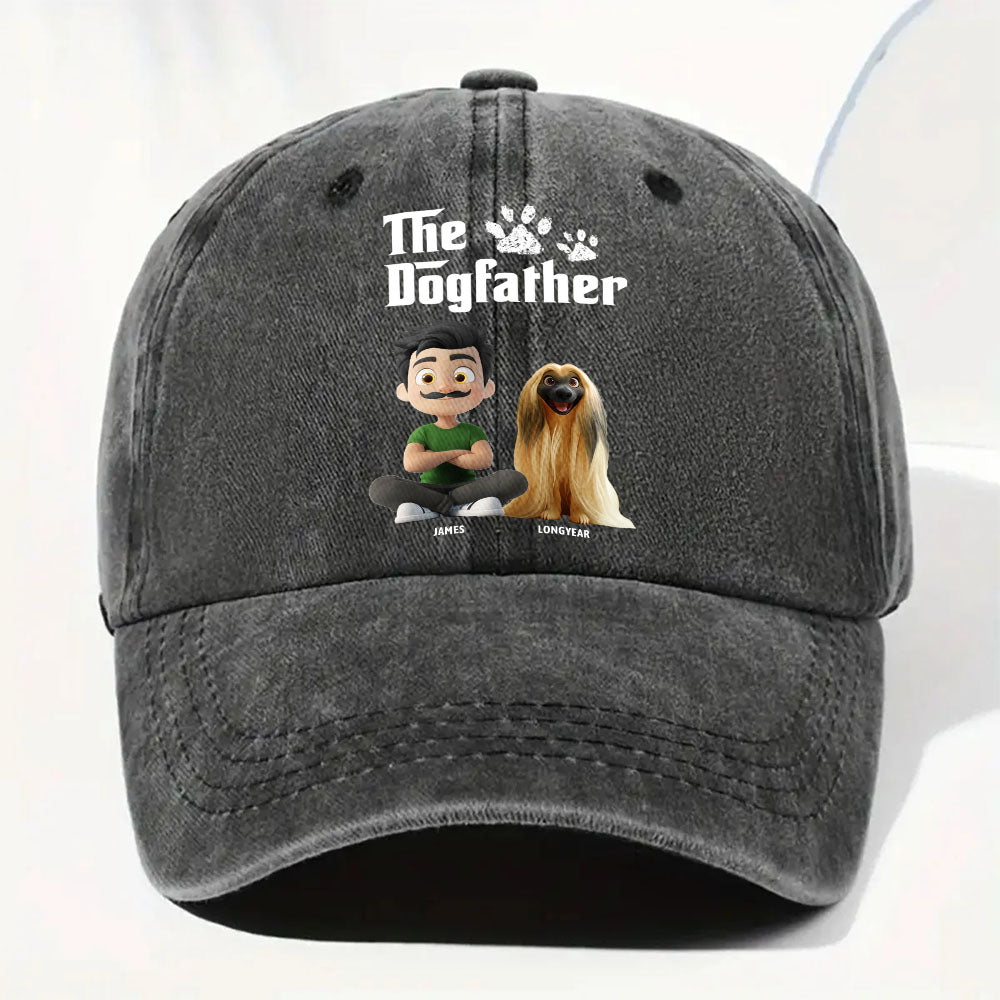 A dark gray washed baseball cap featuring a custom graphic print with the text 'The Dogfather' and cartoon illustrations of a man and a dog, shown against a plain white background.
