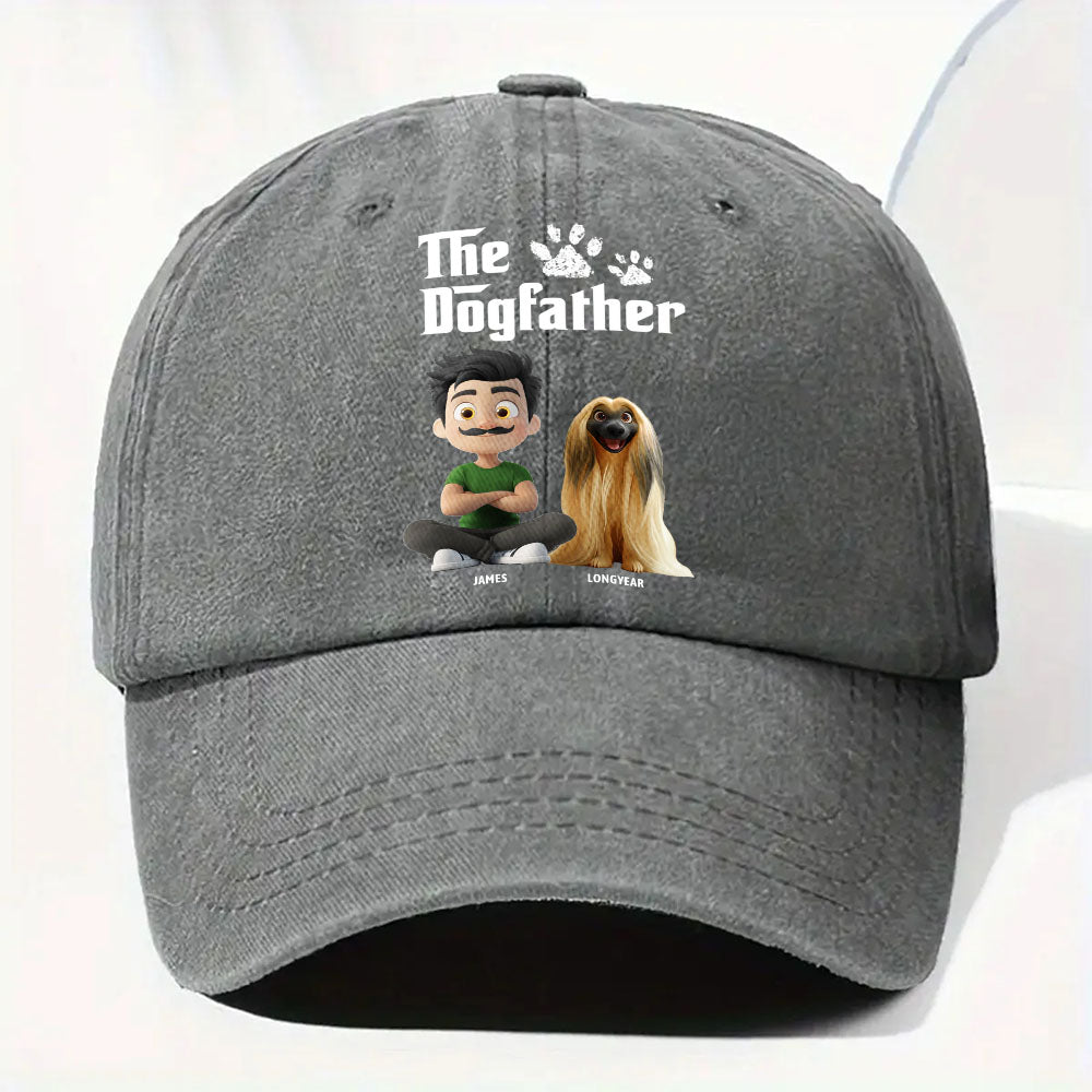 A dark gray baseball cap featuring a custom printed graphic on the front with the text 'The Dogfather' in white, a small crown, and cartoon illustrations of a man and a golden dog.