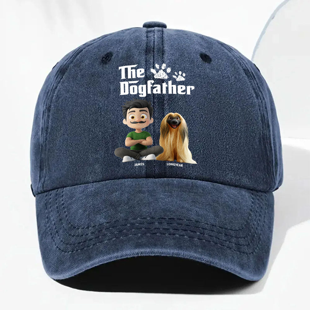 A navy blue washed baseball cap featuring a custom graphic print on the front with the text 'The Dogfather' and cartoon illustrations of a man and a dog.
