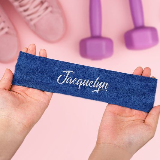 Blue resistance band with 'Jacquelyn' branding held by hands on a pink background with dumbbells.