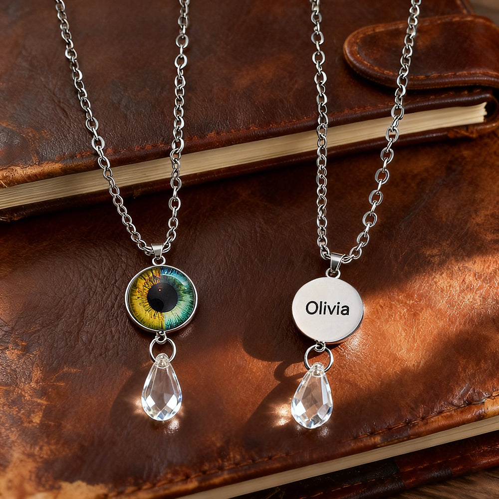 Two necklaces with eye-shaped and circular pendants on a brown leather surface.