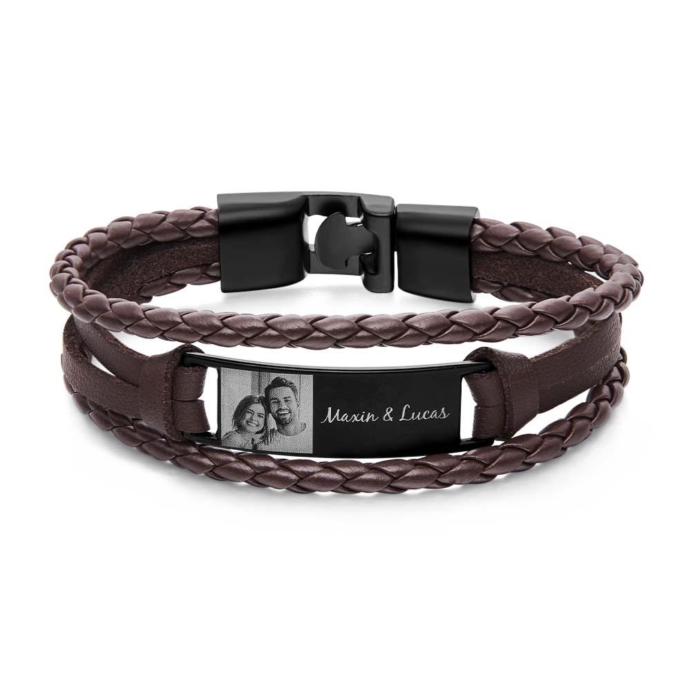 Brown braided leather bracelet with a black clasp and engraved tag on a white background