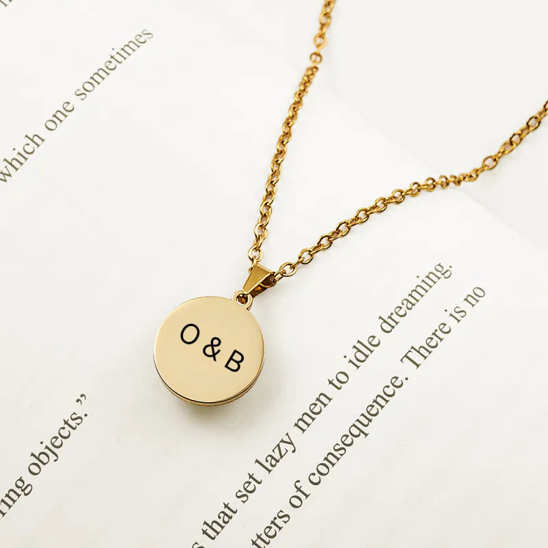 Gold necklace with round pendant featuring initials on a white background with text.