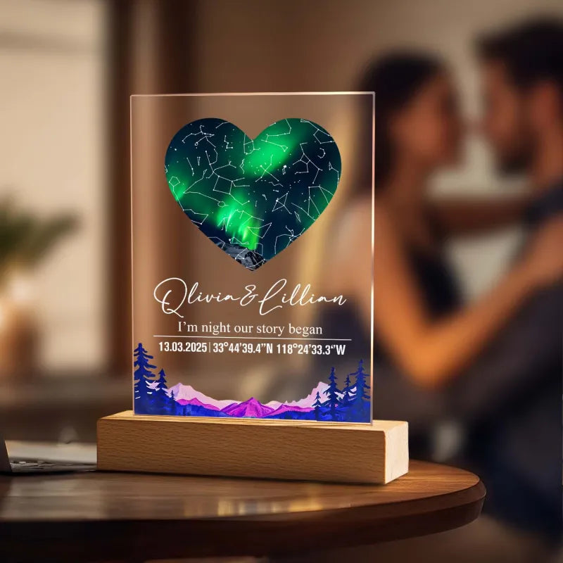 Heart-shaped LED light with personalized text on a wooden base, blurred background of people embracing.