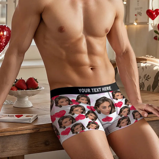 Man wearing underwear with printed faces and hearts, standing in a room with a table and heart decorations.
