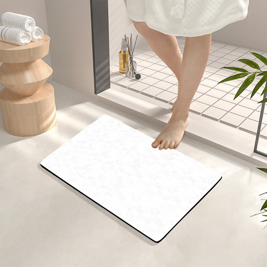 White bath mat on a bathroom floor with a person stepping onto it.